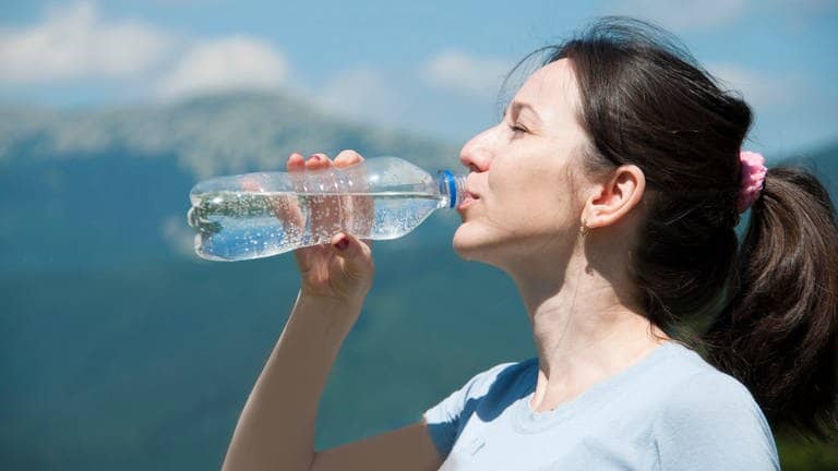 Frau trinkt Wasser vorm Hintergrund der Berge (Foto: Adobe Stock, syhin_stas)