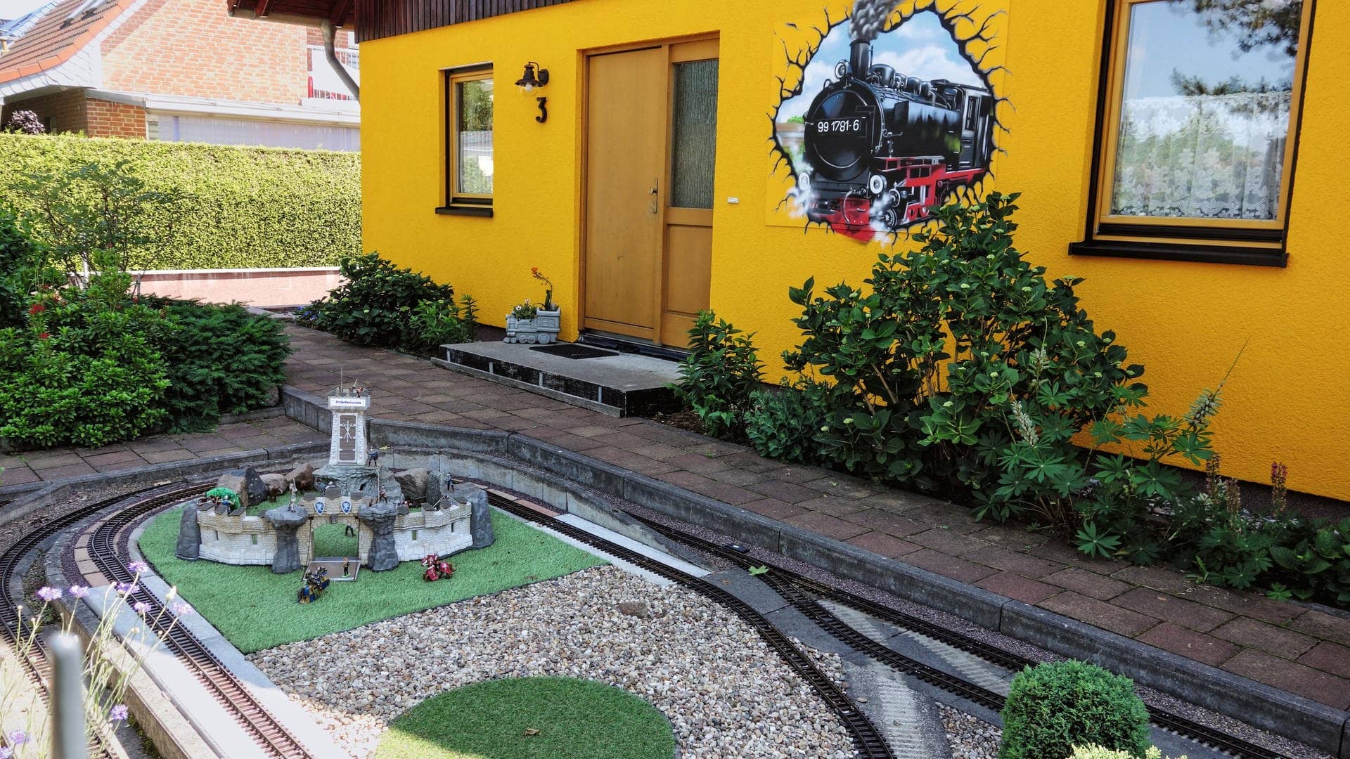 Der Garten eines Hauses in Berlin, durch den Miniatur-Eisenbahnschienen verlegt sind.