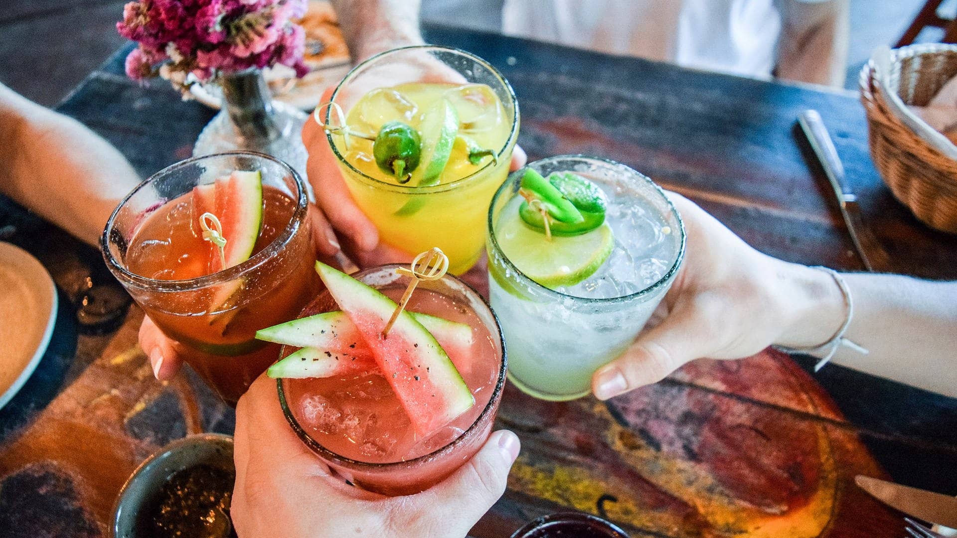 Sommerlich bunte Cocktail-Gläser, dekoriert wie im Urlaub mit verschiedenen Obstsorten