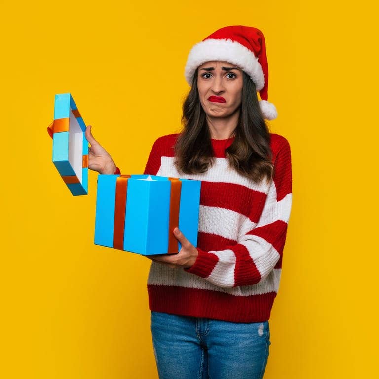 Online Rückgaberecht: Das kannst du tun, wenn dir dein Weihnachtsgeschenk nicht gefällt. Wie der Frau auf dem Bild, die eine Geschenkbox hält und sich nicht freut