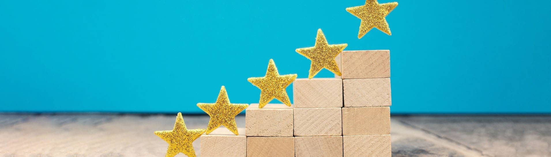 Goldene Sterne werden auf ein Podest aus Holzklötzen gestellt, damit Rezensionen dargestellt werden können. Wir kennen sie von Google-Bewertungen.