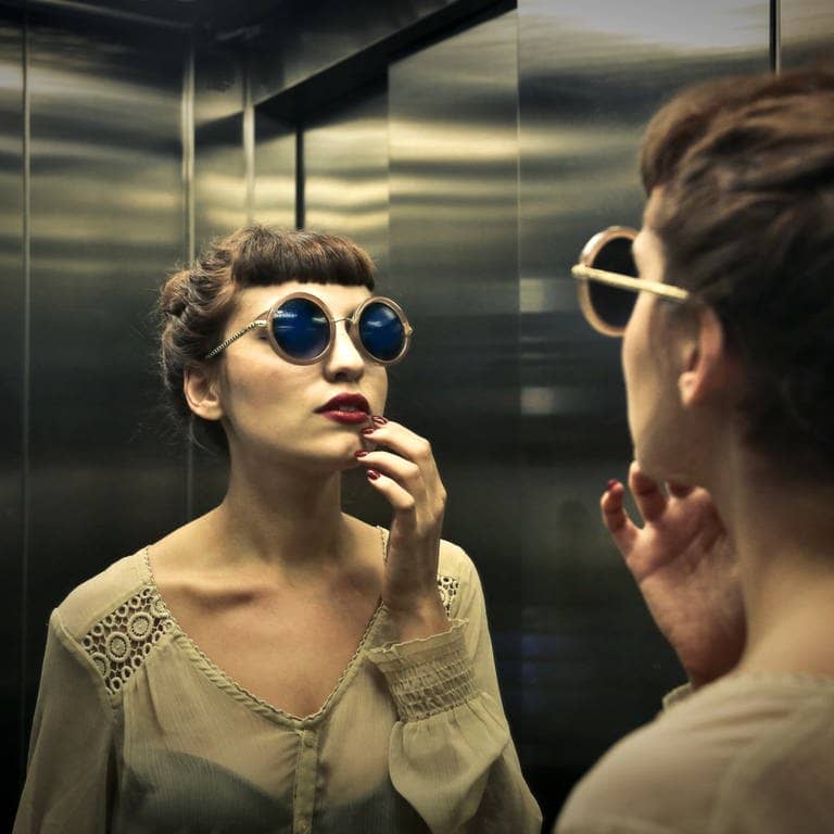 Frau betrachtet sich im Spiegel des Aufzugs