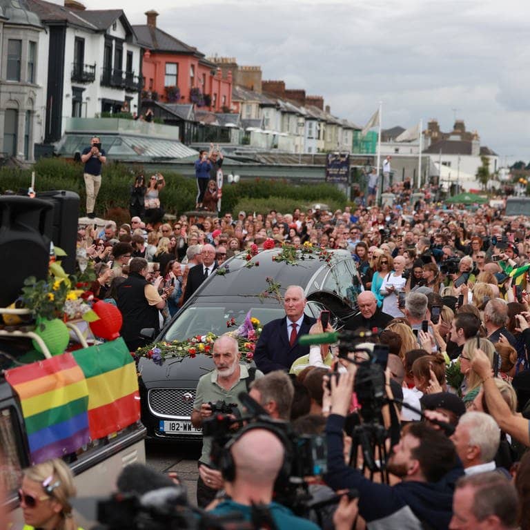 Fans der Sängerin Sinead O'Connor säumen die Straßen, um sich ein letztes Mal von der irischen Sängerin zu verabschieden, als ihr Trauerzug vor der privaten Beerdigung durch ihre frühere Heimatstadt fährt.
