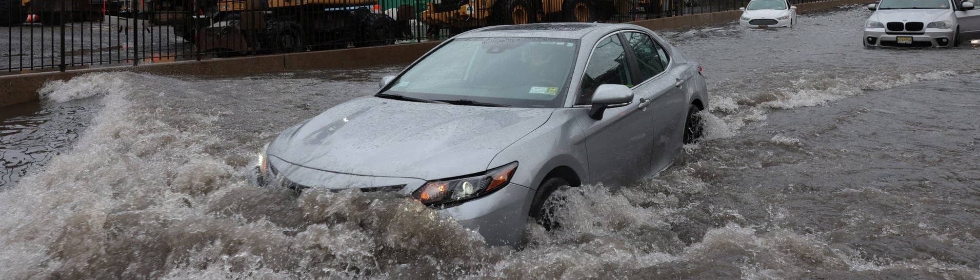 Ein Auto fährt über eine überflutete Straße vor der Williamsburg Bridge in New York City