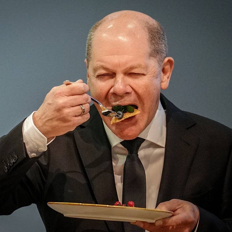 Bundeskanzler Olaf Scholz (SPD) führt eine Gabel mit Essen zum Mund.