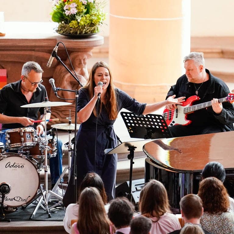 Sängerin Tine Wiechmann singt mit ihrer Band im Hintergrund in der Heiliggeistkirche während eines Taylor-Swift-Gottesdienstes.