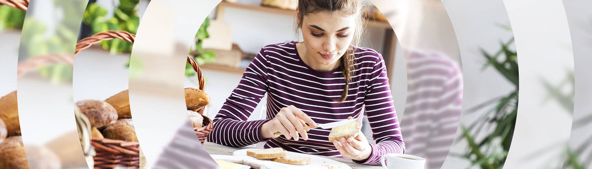 Junge Frau sitzt in der Küche am Frühstückstisch und schmiert sich ein Brot mit Butter
