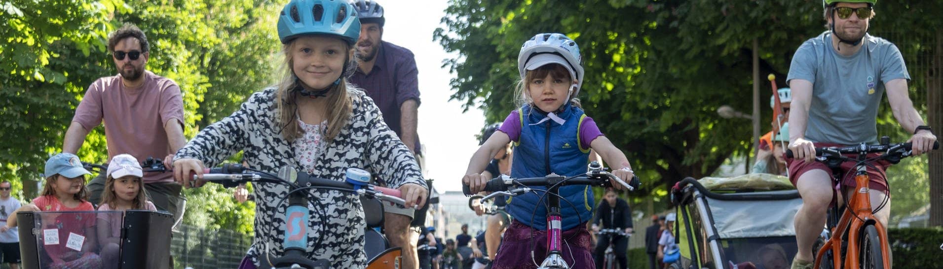 Kinder fahren mit ihren Eltern auf der Straße mit ihren Fahrrädern