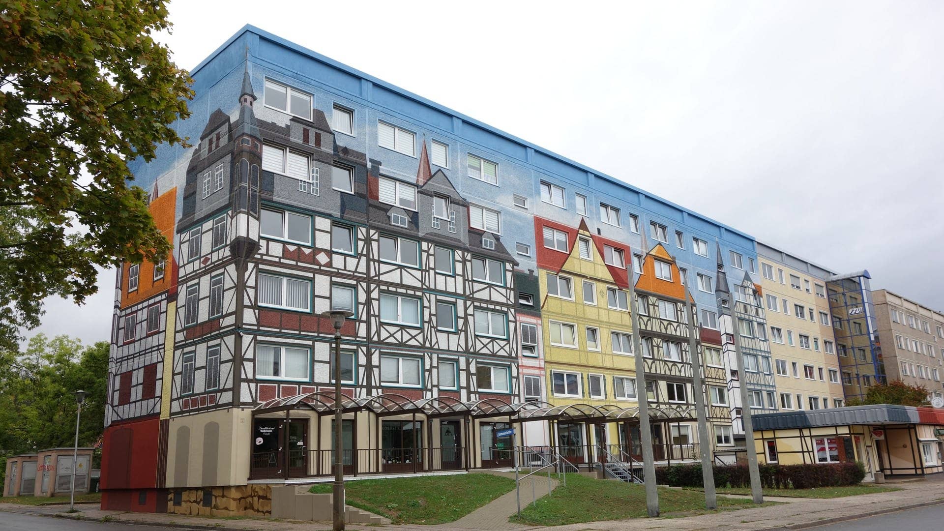 Ein Plattenbau in Gera, dessen Fassade mit einem Fachwerdorf bemalt ist.