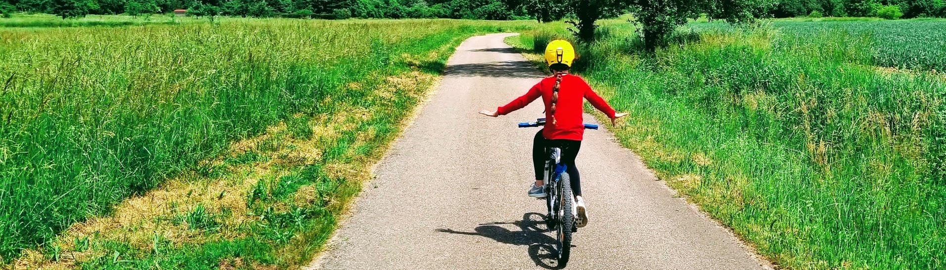 Ein Kind auf einem Fahrrad fährt auf einem Feldweg bei gutem Wetter