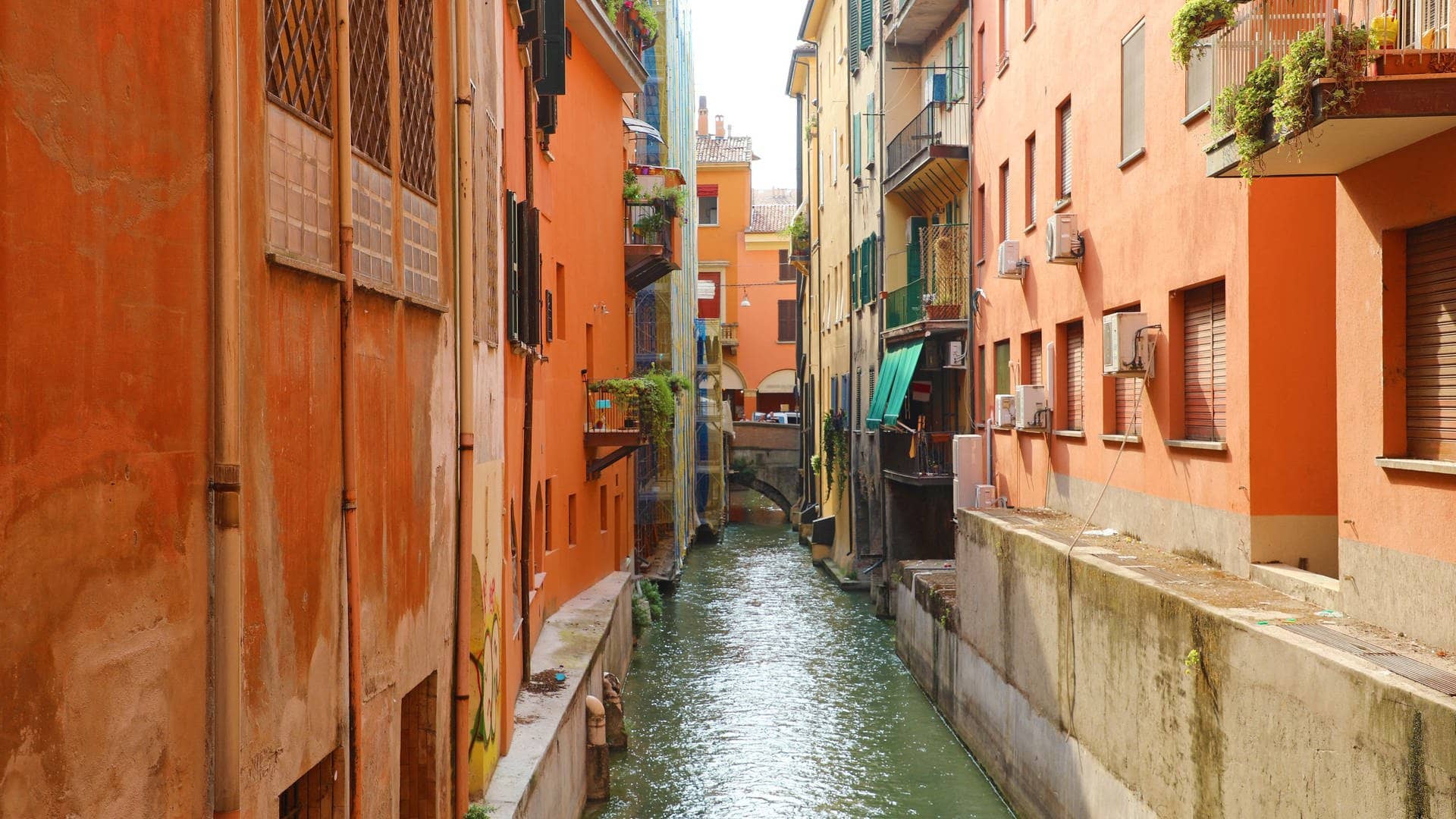 Italien-Städtetrip mal anders: Kanäle fließen durch die Gassen der Stadt zwischen Häuserreihen mit kleinen Balkonen an vielen Wohnungen und schöner Altstadt.