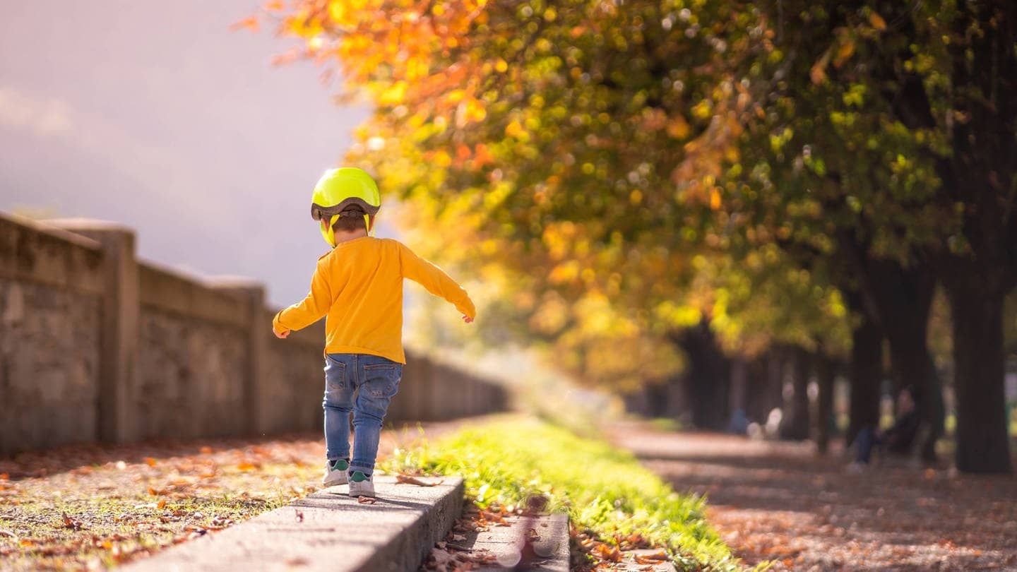 Junge spaziert im Herbst durch bunte Blätter