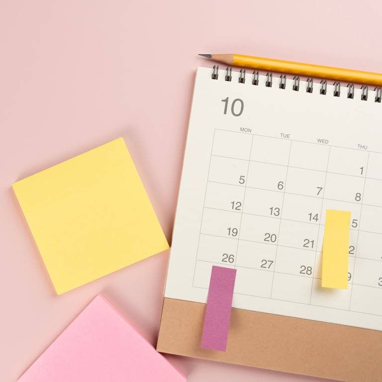 Urlaub fürs nächste Jahr planen – ein Kalender mit Post-it-Zetteln liegt auf dem Tisch. Mit den Feiertagen und Brückentagen die Möglichkeiten optimal nutzen.