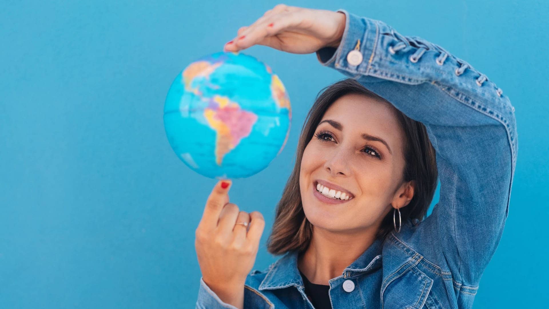 Junge Frau hält einen Globus in der Hand, sie entdeckt kuriose Redewendungen aus anderen Sprachen der Welt.