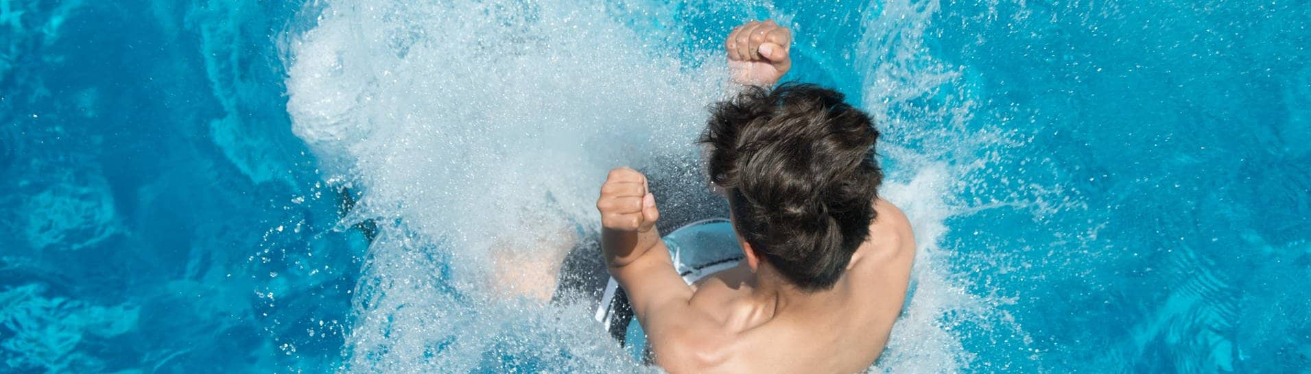 Hitze im Sommer: Ein Mann springt von einem Sprungturm in ein Schwimmbecken.