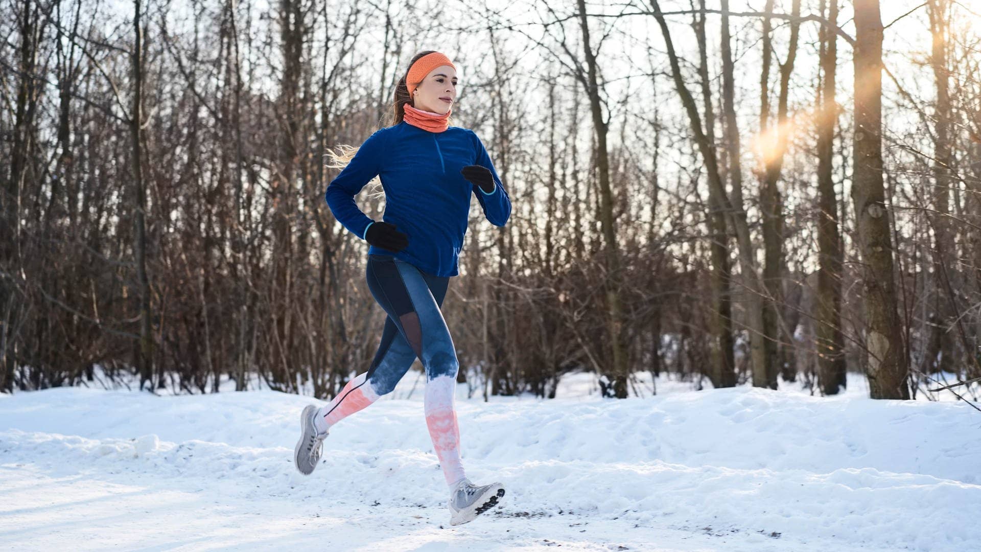 Junge Frau joggt im Winter durch den Schnee. Ein Mythos, der nicht stimmt: dass der Körper bei Kälte mehr Kalorien verbrennt.