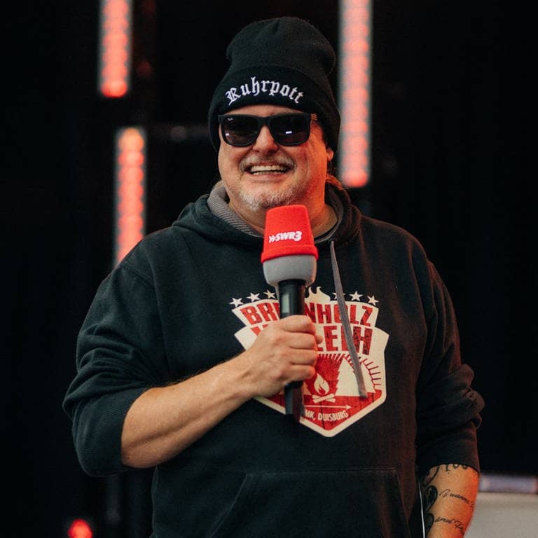 Comedian Markus Krebs hält ein SWR3-Mikrofon in der Hand und lacht. (Foto: SWR3)