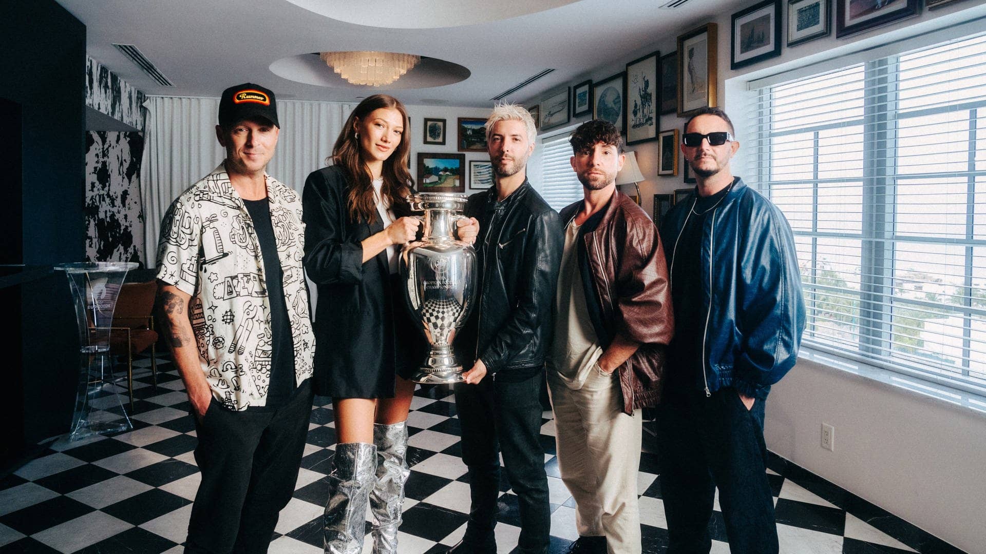 One Republic-Sänger Ryan Tedder, Sängerin Leon und das DJ-Trio Meduza halten den EM-Pokal in der Hand, die Gruppe hat den offiziellen EM-Song  „Fire“ produziert