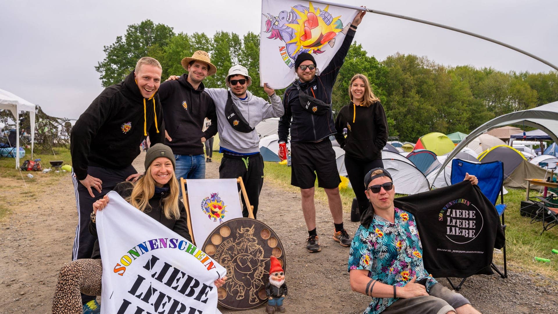 Eine Gruppe aus Menschen auf dem Campingplatz von Rock am Ring zeigt Flaggen und Pullis mit der Aufschrift Liebe