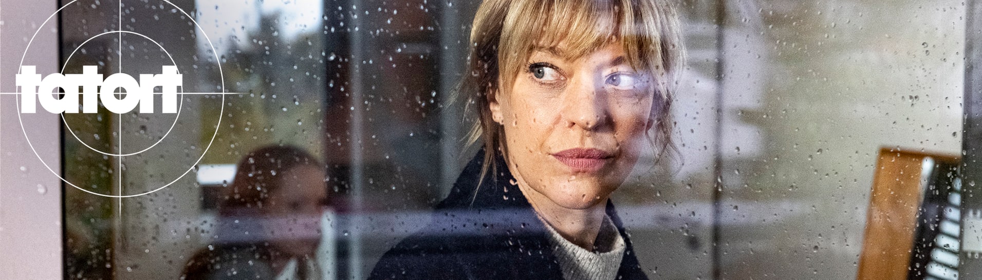 Tatort-Kritik Mainz „Aus dem Dunkel“: Kommissarin Berlinger schaut aus einem verregneten Fenster. Im Hintergrund sitzt ein kleines Mädchen.