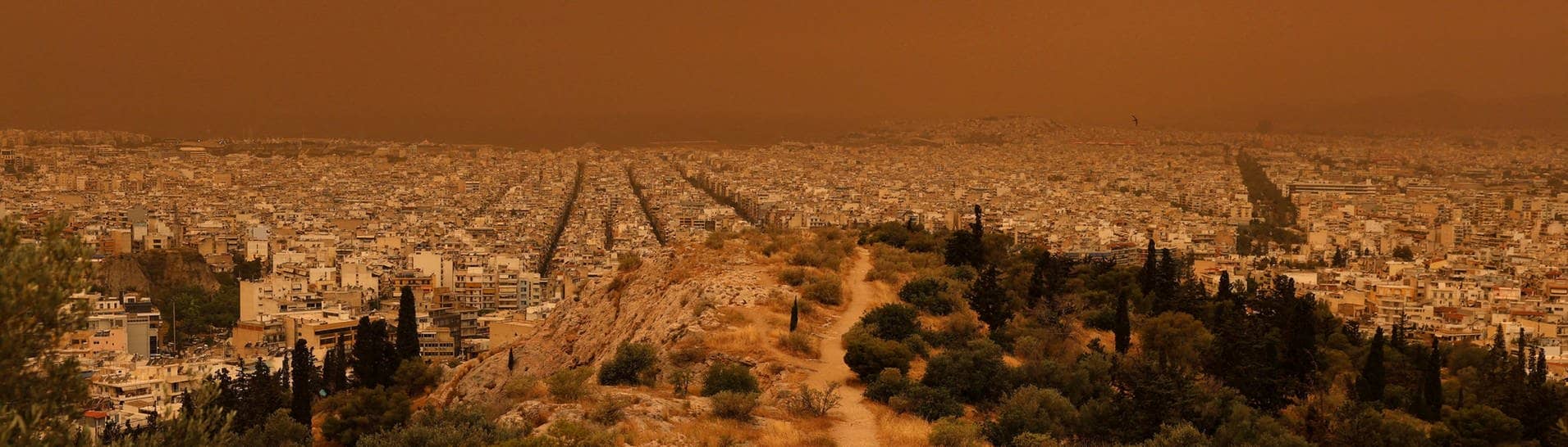 Roter Himmel, rote Erde: Ein Mann wandert am Dienstag in den Hügeln über Athen.
