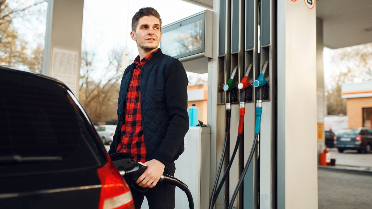 Mann steht an der Tankstelle und tankt