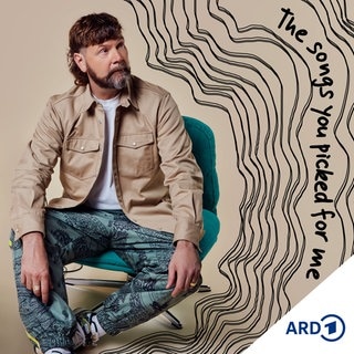 Portrait Rea Garvey sitzt auf einem Stuhl und schaut zur Seite 