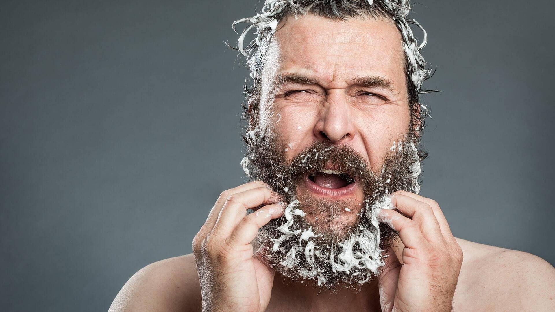 Mann mit Bart kämpft mit Anti-Schuppen-Shampoo (Foto: imago / Photocase)