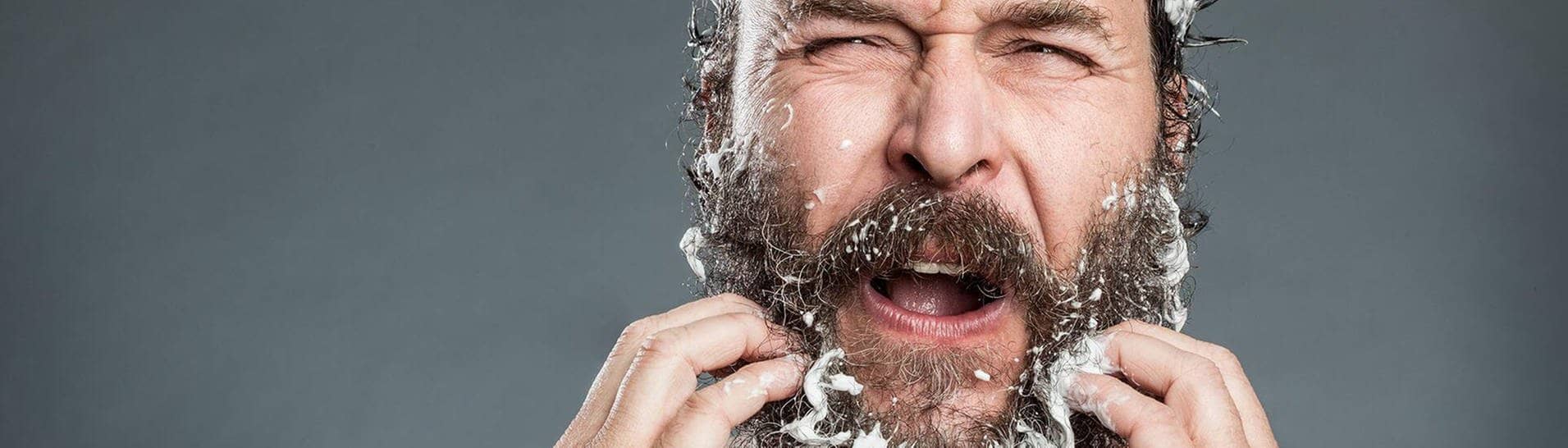 Mann mit Bart kämpft mit Anti-Schuppen-Shampoo (Foto: imago / Photocase)
