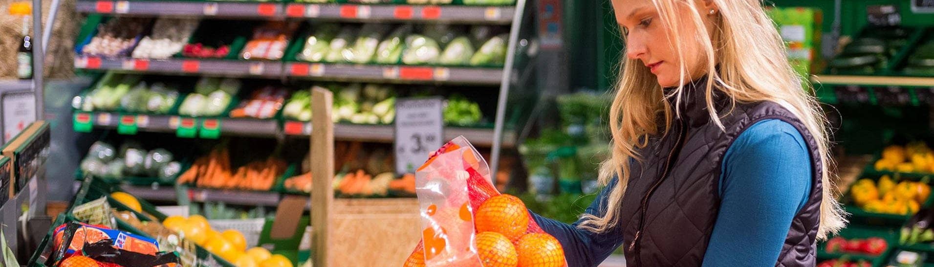 Eine Frau vergleicht in einem Supermarkt ein Netz Orangen (Foto: dpa/picture-alliance.de/Benjamin Nolte)