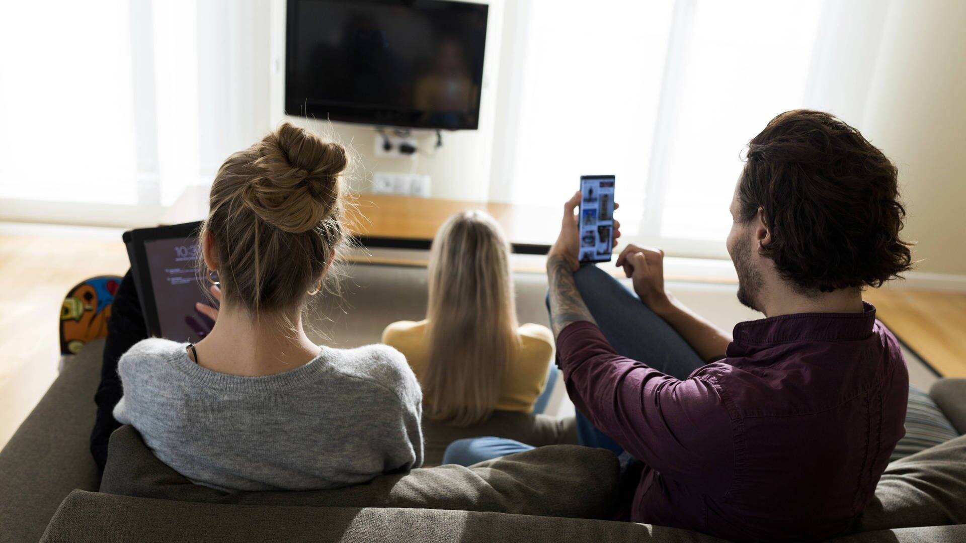 Menschen mit unterschiedlichen technischen Geräten wie Smartphone, Tablet und Fernseher (Foto: IMAGO, IMAGO / Westend61)