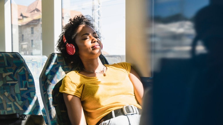 Frau fährt im Sommer mit der Bahn im Nahverkehr (Foto: IMAGO, Westend61)