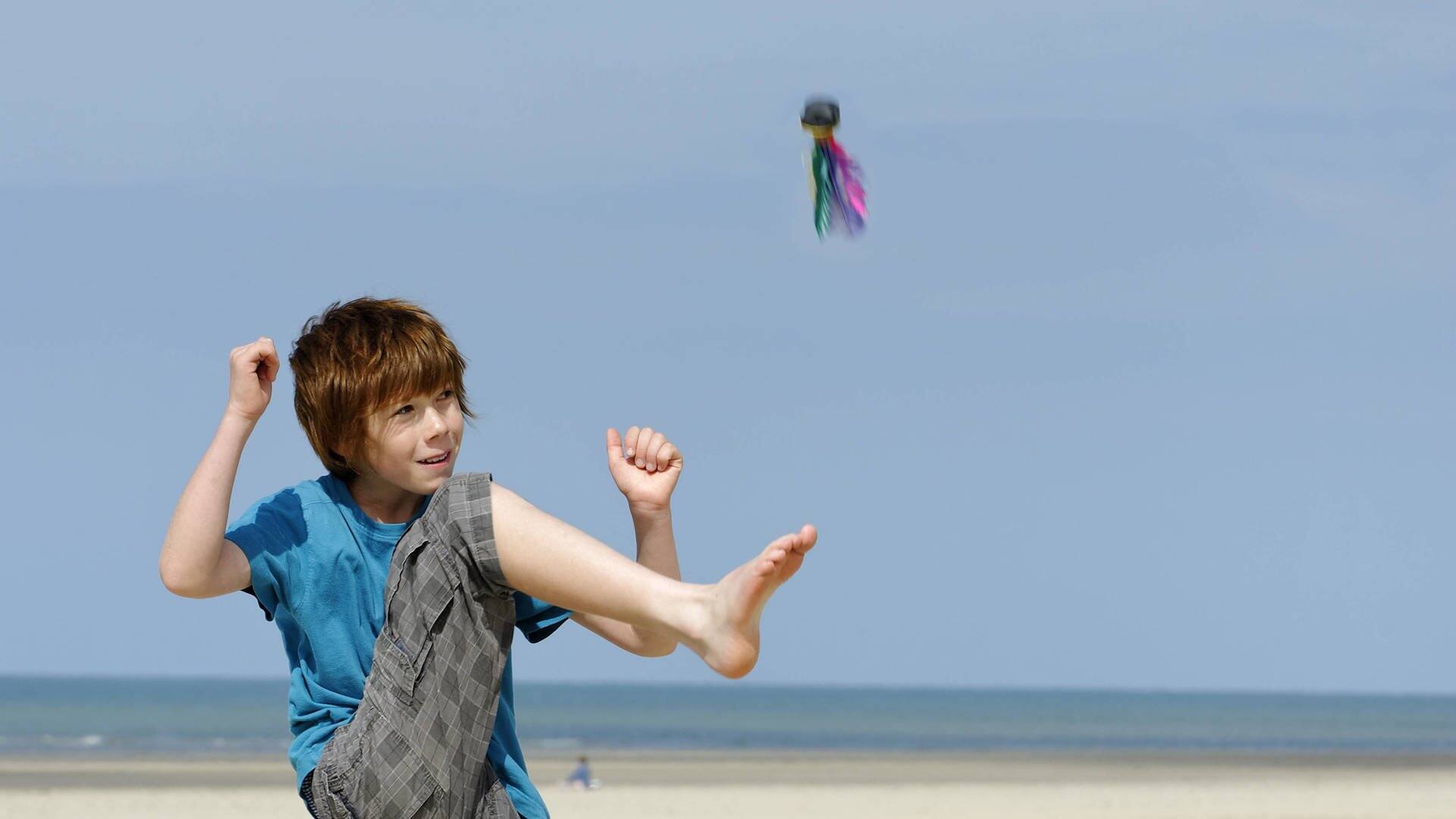Junge kickt Indiaca-Ball an einem Strand in die Luft (Foto: IMAGO, Westend61)