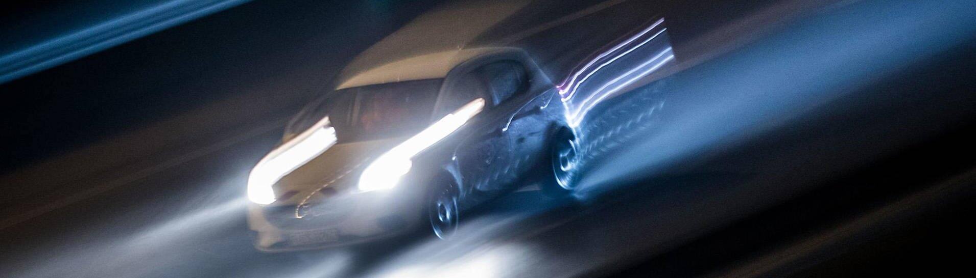 Schnell fahrendes Auto in der Nacht (Foto: dpa/picture-alliance)