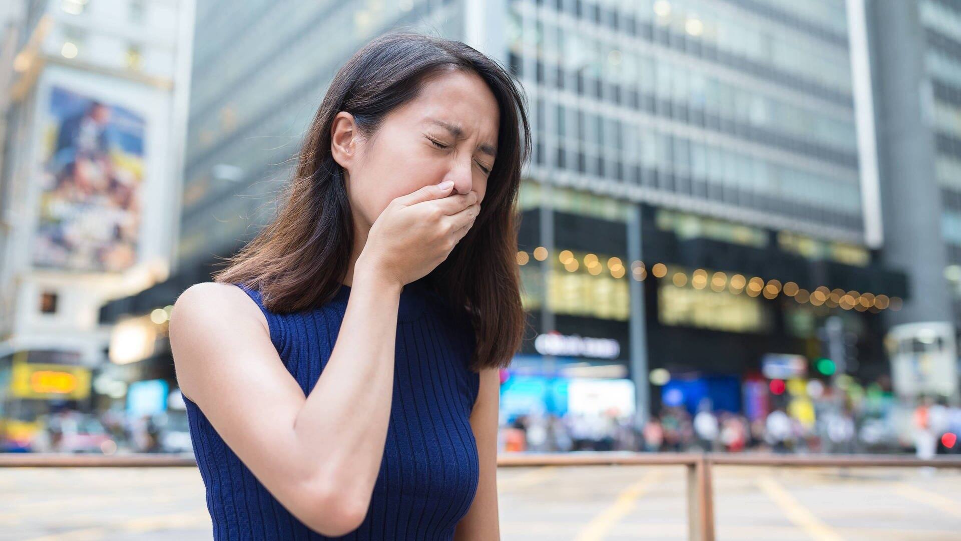 Asiatische Frau vor Großstadtkulisse hat Übelkeit und die hand vor dem Mund (Foto: picture-alliance / Reportdienste, picture alliance / PantherMedia | Leung Cho Pan)