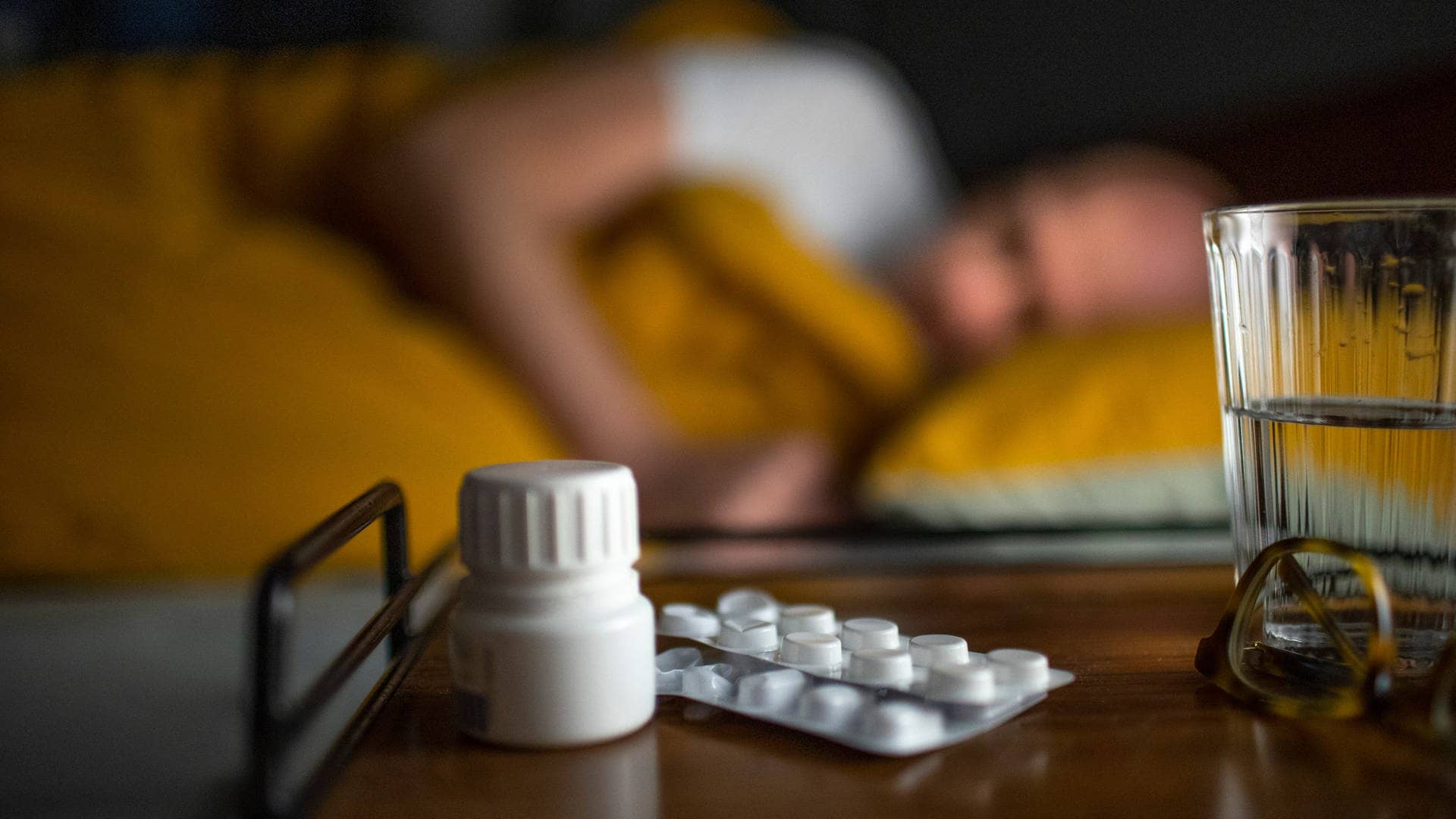 Ein Mann liegt mit Migräne im Bett, im Vordergrund Medikamente (Foto: picture-alliance / Reportdienste, picture alliance / photothek | Ute Grabowsky)