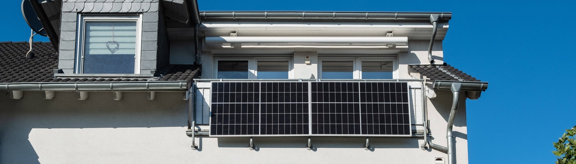 Mehrfamilienhaus mit zwei Solarpanelen am Balkongeländer (Foto: IMAGO, Robert Poorten)