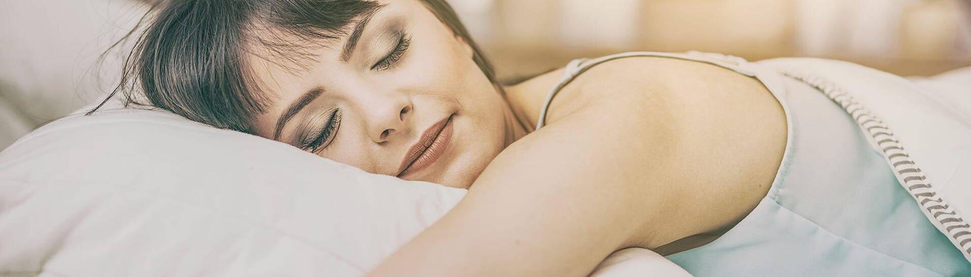 Eine Frau liegt gemütlich auf ihrem Kopfkissen im Bett (Foto: Adobe Stock/REDPIXEL)