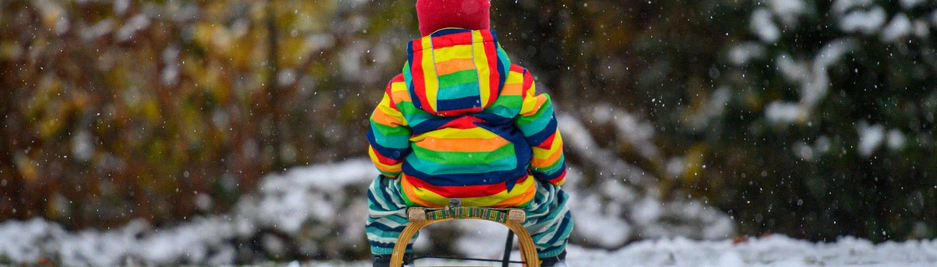 Kind von hinten auf einem Holzschlitten (Foto: IMAGO, Kirchner-Media)