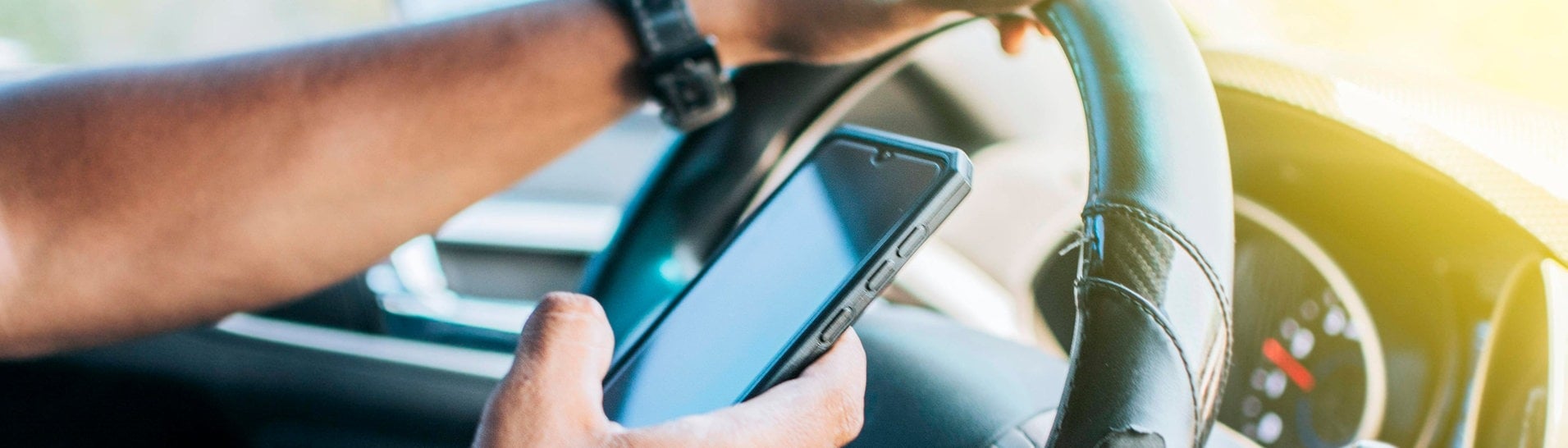 Mann hält Telefon am Steuer in der Hand (Foto: IMAGO, imagebroker)