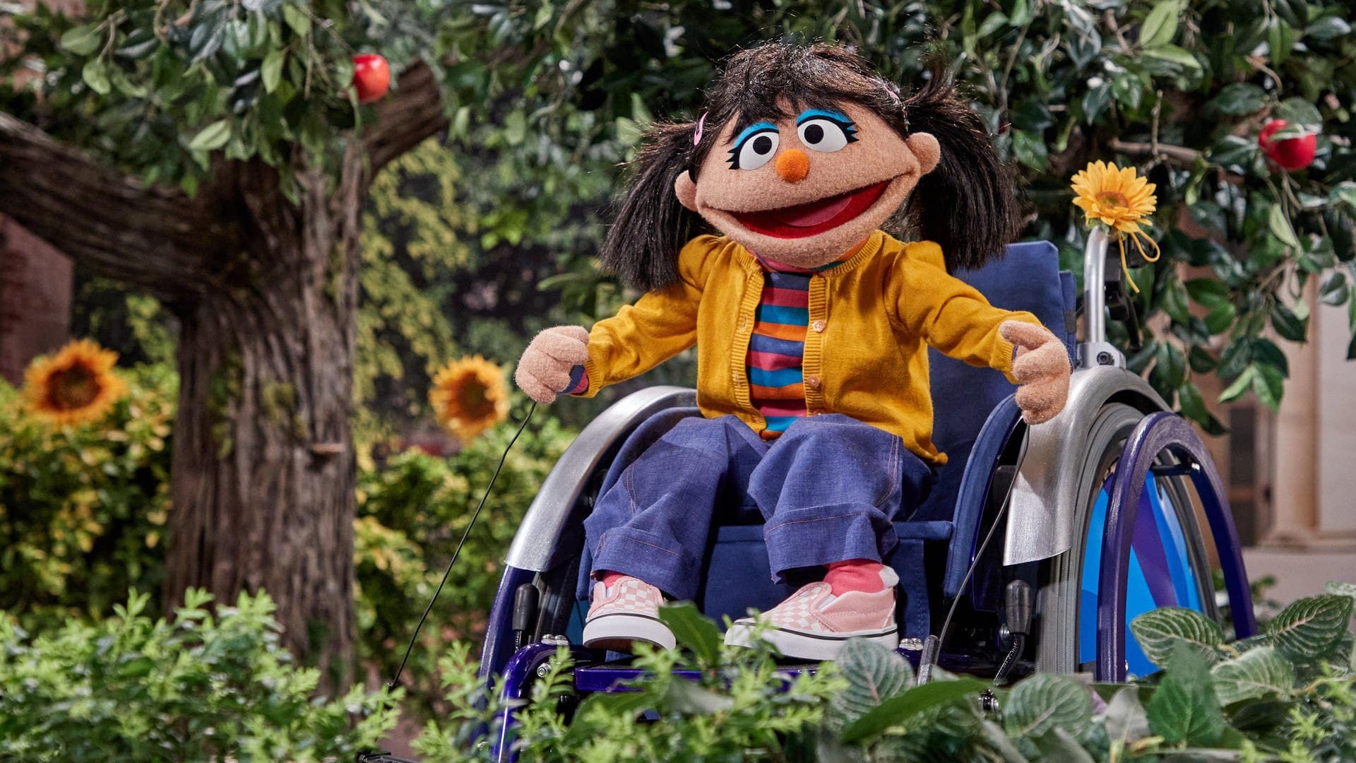 Neue Puppe der Sesamstraße sitzt im Rollstuhl. Sie trägt zwei braune Zöpfe, eine gelbe Jacke und eine blaue Hose. (Foto: picture-alliance / Reportdienste, picture alliance/dpa | Georg Wendt)