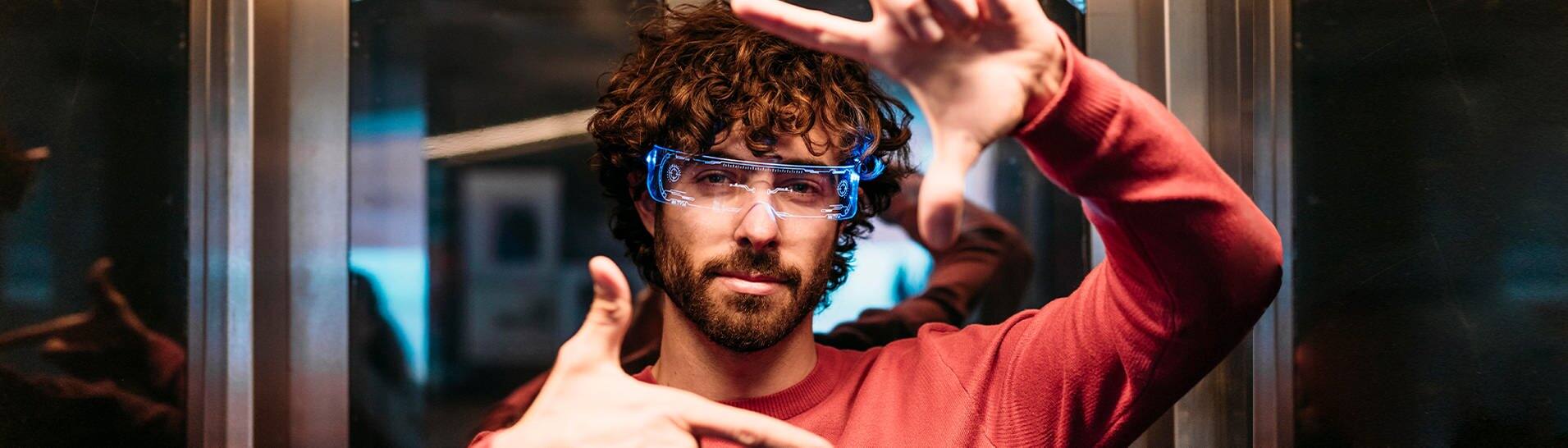 Ein Mann mit rotem Oberteil hat eine smarte Brille auf, die mit künstlicher Intelligenz funktioniert (Foto: picture-alliance / Reportdienste, picture alliance / Westend61 | Eva Blanco)
