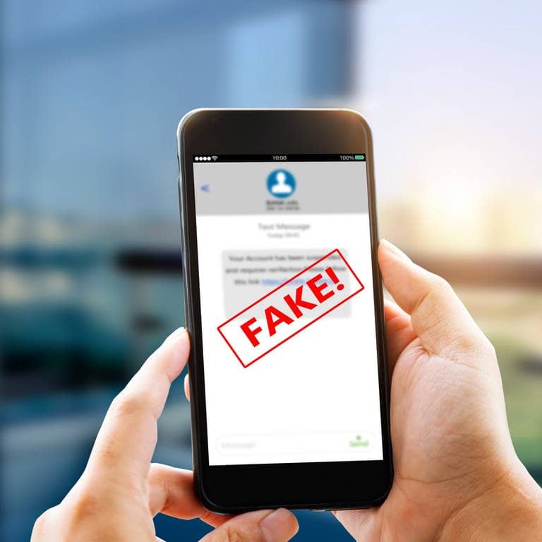 Person hält Smartphone in der Hand auf der eine SMS abgebildet ist, ein roter Fake-Banner ist darüber (Foto: Adobe Stock, Adobe Stock // panuwat)