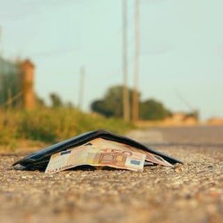 Verlorenes Portemonnaie mit Geld wartet auf einer Straße auf den Finder