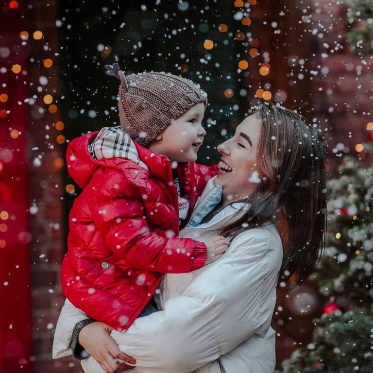 Mutter mit Kind im Schnee. So wünschen wir es uns für 2023: Weiße Weihnachten. Die Prognosen dazu gibt bei SWR3. (Foto: IMAGO, IMAGO / Westend61)