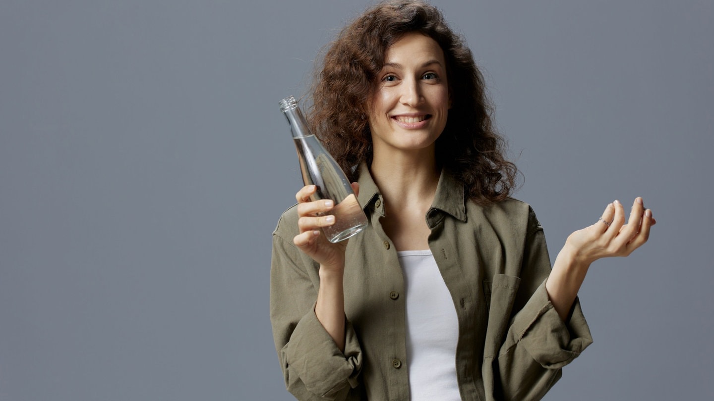 Frau hält ein Glas mit Leitungswasser in der Hand und fragt sich, welche Mythen stimmen. (Foto: IMAGO, Pond5 Images)