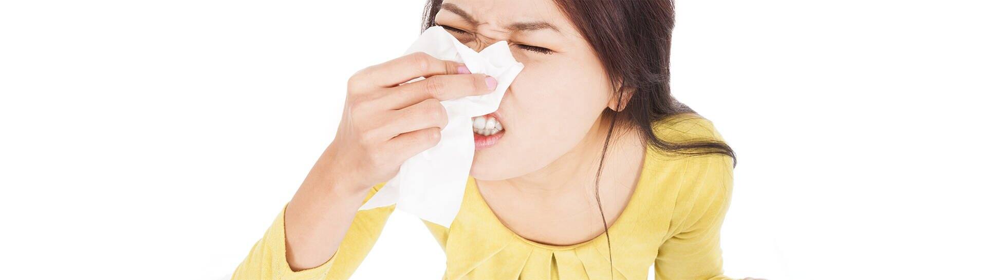 Frau, die ihre Augen geschlossen hat und in ein Taschentuch niest  (Foto: Adobe Stock / Tom Wang)