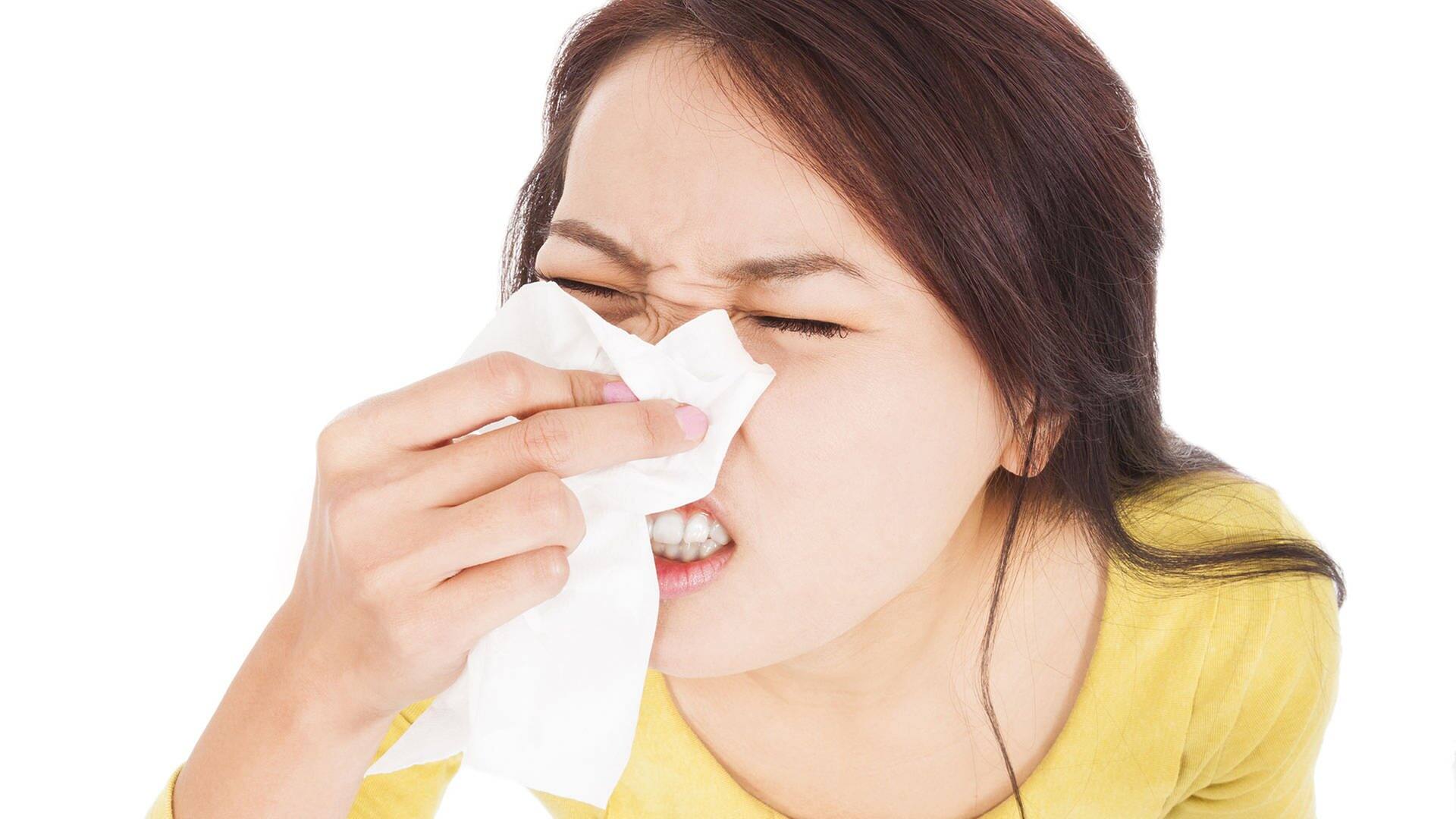 Frau, die ihre Augen geschlossen hat und in ein Taschentuch niest  (Foto: Adobe Stock / Tom Wang)