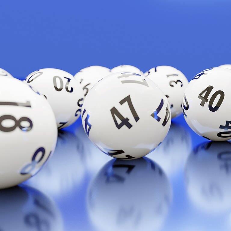 Verschiedene Bälle aus der Lotterie auf einem blauen Untergrund  (Foto: Adobe Stock / Fiedels)