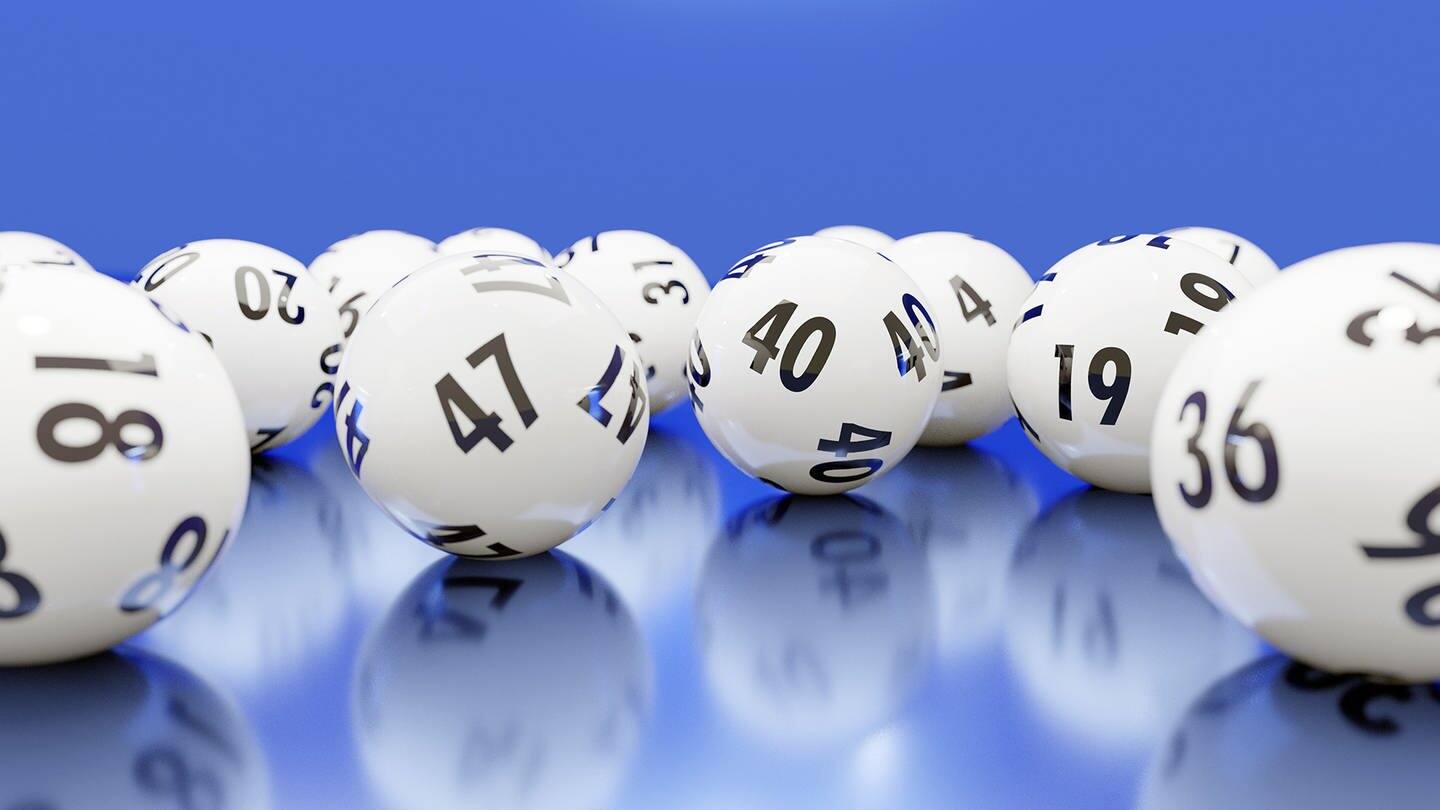 Verschiedene Bälle aus der Lotterie auf einem blauen Untergrund  (Foto: Adobe Stock / Fiedels)